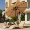 A couple resting under the 9ft Round Tilt Patio Umbrella with Solar LED Light-Beige with lounge chairs
