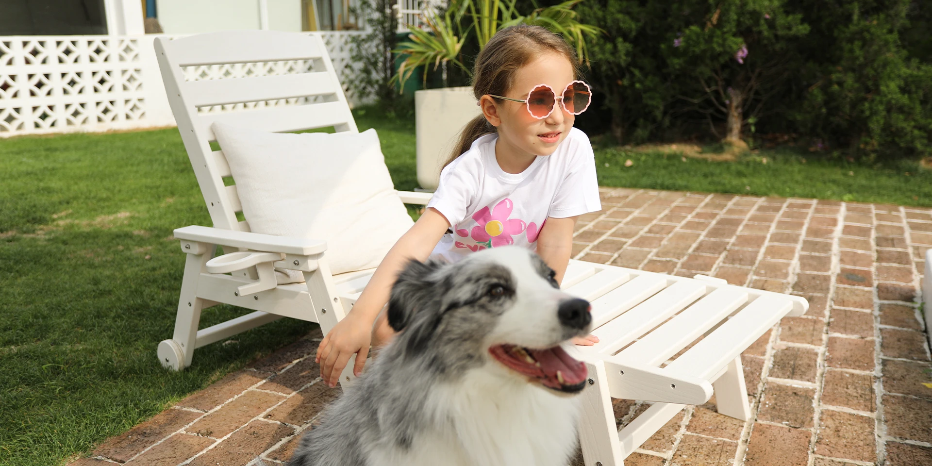 Little girl sit on the chaise lounge with her dog