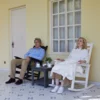 A couple resting on the Vintage Porch Rocking Chair at the front porch