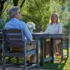 A couple sitting at the 67″ x 32″ Rectangle Outdoor Dining Table-Dark Gray in the garden
