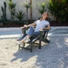 A woman resting on the HDPE Reclining Folding Adirondack Chair with Ottoman-Dark Gray in the backyard