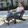 A woman sitting on the HDPE Reclining Folding Adirondack Chair with Ottoman-Dark Gray in the yard