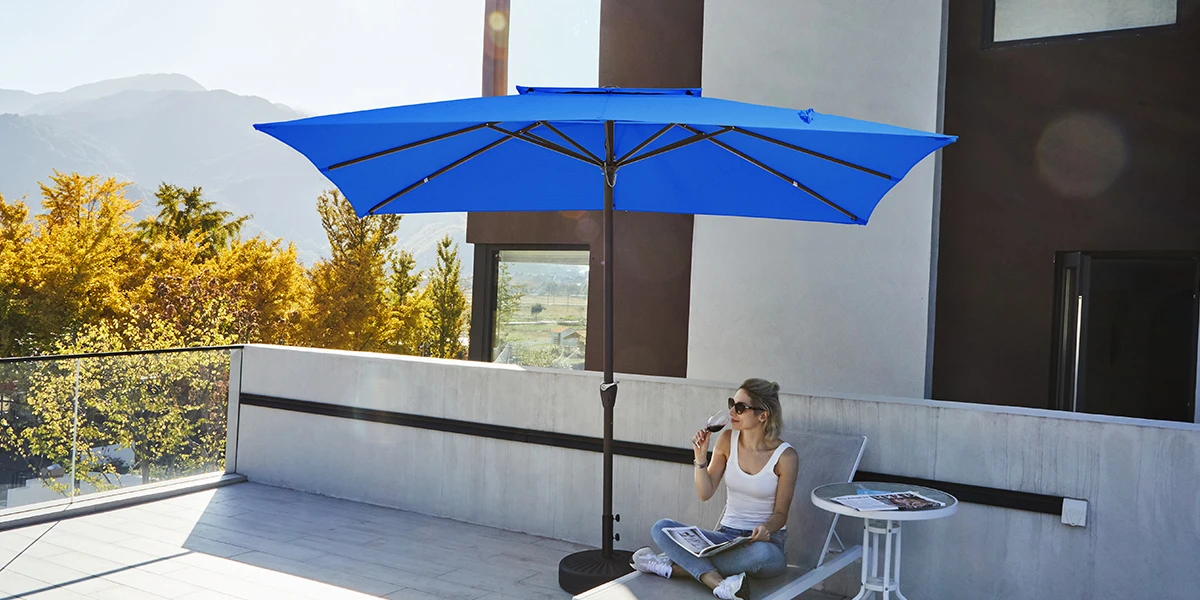 A woman wearing sunglasses sits in the blue rectangular patio market umbrella