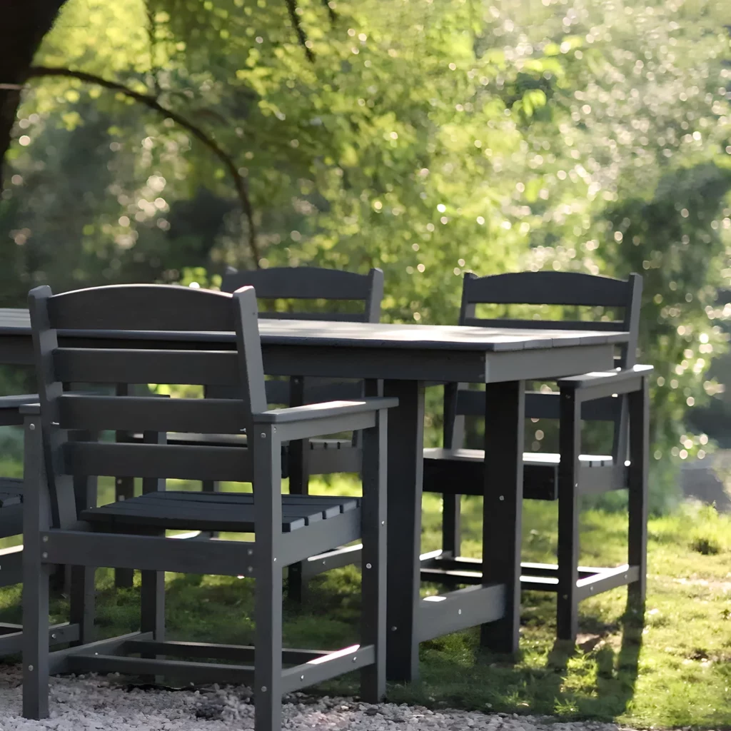 The GRANGE 32 x 67 inch Dining Table and Chairs are set up on a lawn covered with pebbles.