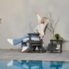A woman relaxing on the Outdoor Adirondack Swivel Glider Chair-Dark Gray