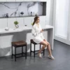 A woman sitting on the 24″ Counter Height Faux Leather Kitchen Bar Stool Set of 2-Dark Brown
